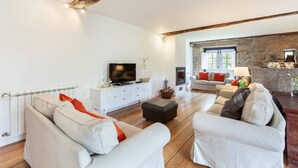 Un salon moderne avec une cheminée, des canapés blancs et un mur d’accent en pierre.
