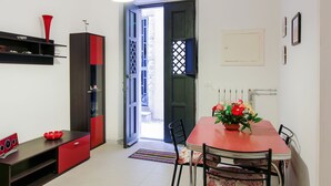 Un coin repas avec une table rouge, des chaises, un vase de fleurs et un meuble noir agrémenté d’une touche de rouge.