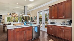 Une cuisine spacieuse avec des meubles en bois, un grand îlot central et une vue sur l’extérieur.