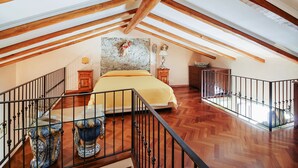 An attic bedroom with a bed, wooden beams, a stone wall, and a view of the sky. - Corso Umberto (Taormina)