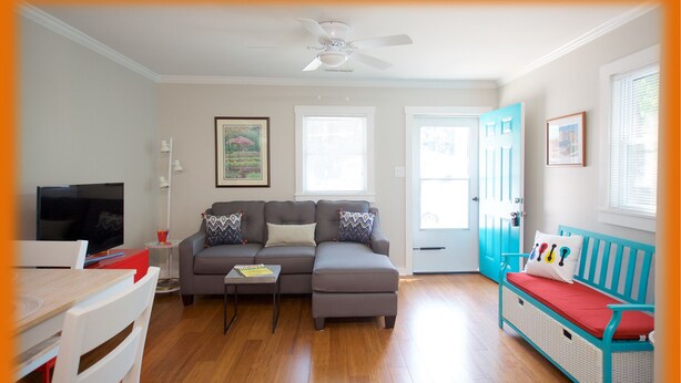 A living room with a sectional sofa, a coffee table, a TV, and a dining area with a table and chairs. - Medical & Work Stay · Quiet · Fenced Pet · Friendly (Durham)