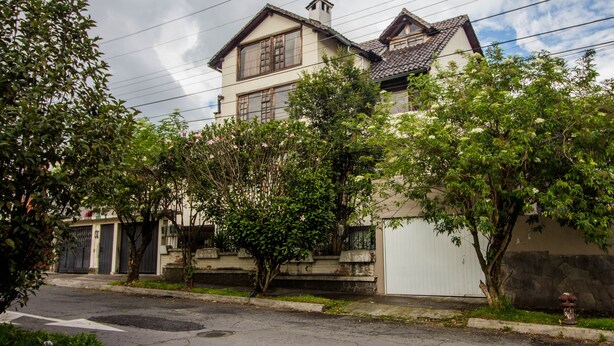 A two-story house with a traditional architectural style, featuring a pitched roof and a chimney. There are trees in front of the house, and a fire hydrant is visible on the right side. - Quiet, spacious and quiet apartment in Quito  (Quito)