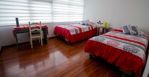 Un dormitorio con dos camas, un escritorio y una silla.