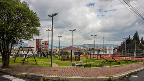 A playground with swings and a climbing structure, surrounded by a brick pavement and a grassy area. - Quiet, spacious and quiet apartment in Quito  (Quito)