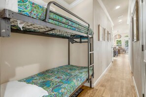 A bunk bed with a colorful patterned bedspread, a ladder, and a wooden floor in a hallway with framed pictures on the wall. - Sunset View at CrossTimbers Marina (Sperry)