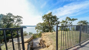 A stone staircase leading to a viewing platform with a metal railing overlooking a body of water and trees. - Sunset View at CrossTimbers Marina (Sperry)