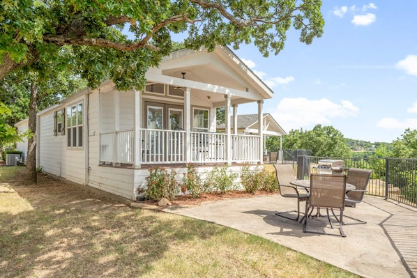 A single-story house with a covered porch, a patio with outdoor furniture, and a view of the surrounding landscape. - Sunset View at CrossTimbers Marina (Sperry)