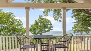 A covered patio with a table and chairs, overlooking a body of water and trees. - Sunset View at CrossTimbers Marina (Sperry)