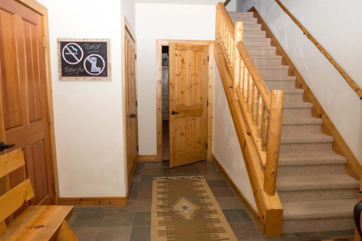 Una escalera de madera con barandilla, un banco de madera, una alfombra y un cartel en la pared.