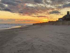 Ein Strand mit einer Holzlattenzaun und einem Gebäude mit einem Turm.