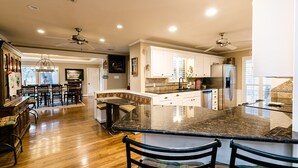 A spacious kitchen with a large island, wooden flooring, white cabinets, and ceiling fans. - Beautiful Country Home Minutes from Magnolia & Baylor Pool HotTub River Front (Crawford)