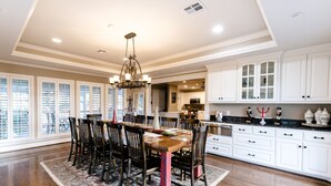 A spacious kitchen with white cabinetry, a dining area with a wooden table and chairs, and a chandelier. - Beautiful Country Home Minutes from Magnolia & Baylor Pool HotTub River Front (Crawford)