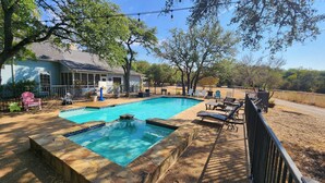 A backyard with a rectangular swimming pool, surrounded by a stone deck, and furnished with lounge chairs and a barbecue area. - Beautiful Country Home Minutes from Magnolia & Baylor Pool HotTub River Front (Crawford)