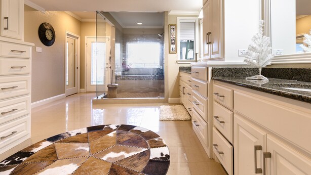 A modern kitchen with white cabinetry, a granite countertop, and a patterned rug. - Beautiful Country Home Minutes from Magnolia & Baylor Pool HotTub River Front (Crawford)