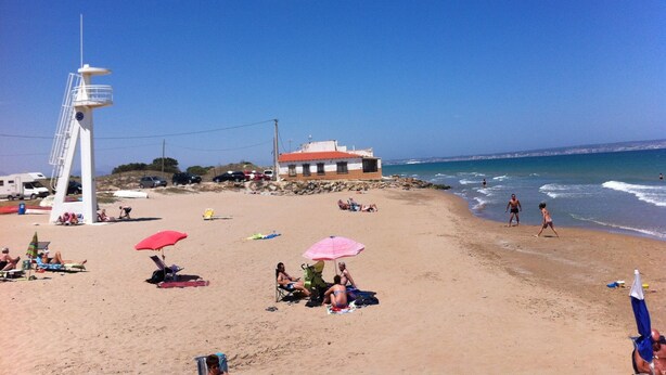 A beach with people sunbathing, umbrellas, and a lifeguard tower. - Villa with pool 7 minutes from the beach walking. WIFI + Air Conditioning (La Marina del Pinet)