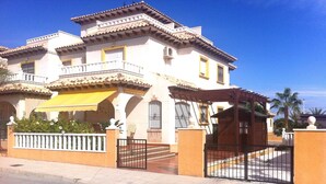 A large, multi-story building with a balcony, a yellow awning, and a gated entrance. - Villa with pool 7 minutes from the beach walking. WIFI + Air Conditioning (La Marina del Pinet)