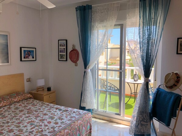 A bedroom with a bed, a nightstand, a lamp, a framed photo, and a window with curtains.