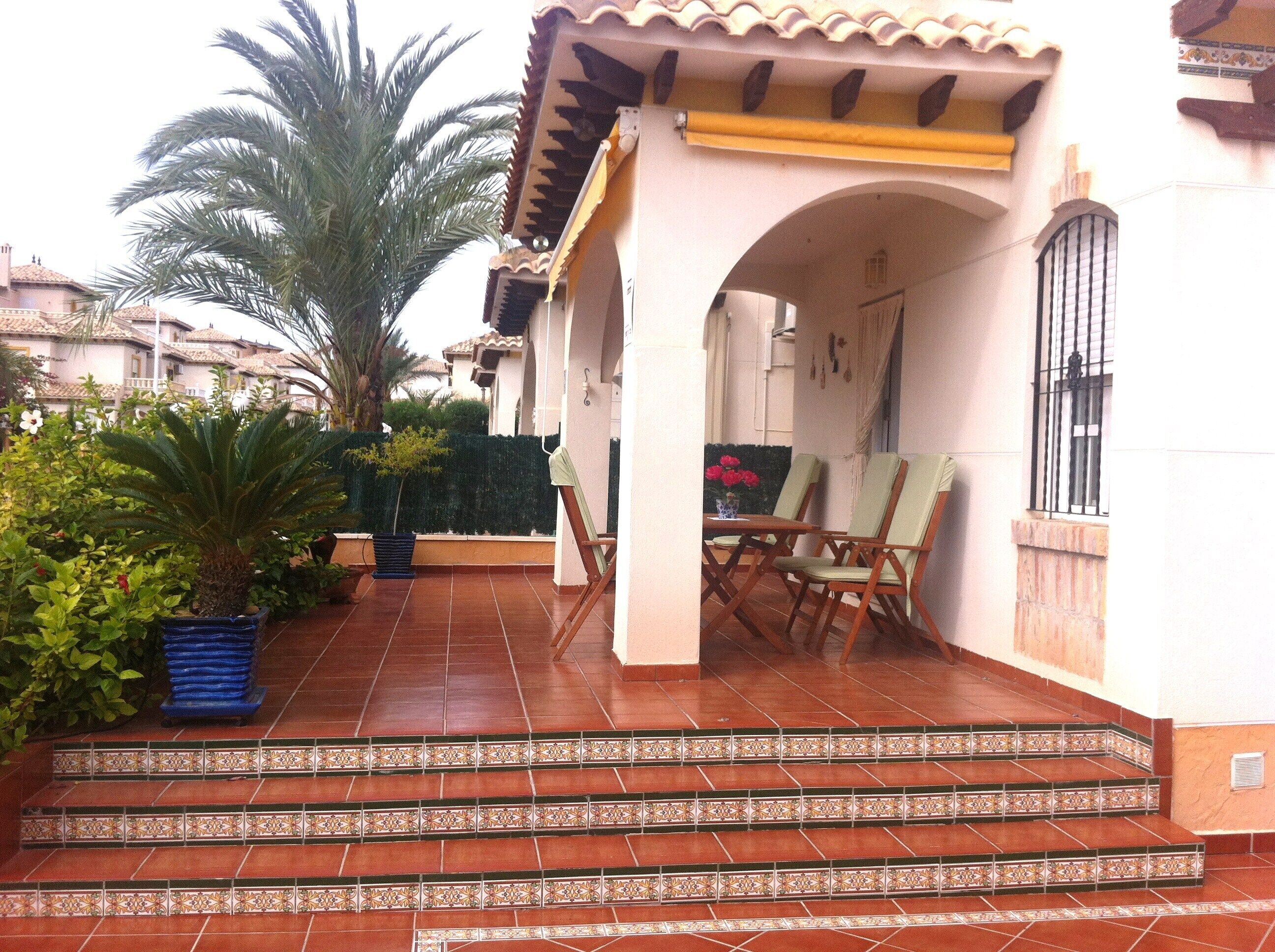 A patio with a tiled floor, a small table with chairs, and a potted plant.