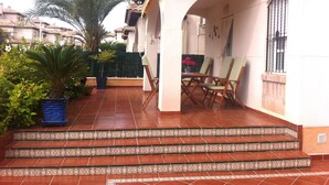 A patio with a tiled floor, a small table with chairs, and a potted plant. - Villa with pool 7 minutes from the beach walking. WIFI + Air Conditioning (La Marina del Pinet)