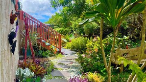 Een tuinpad met stapstenen, omringd door verschillende planten en een rode brug.