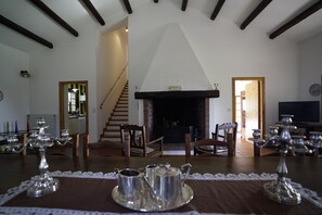 A cozy living room with a fireplace, wooden furniture, and a dining area with a table set for a meal.