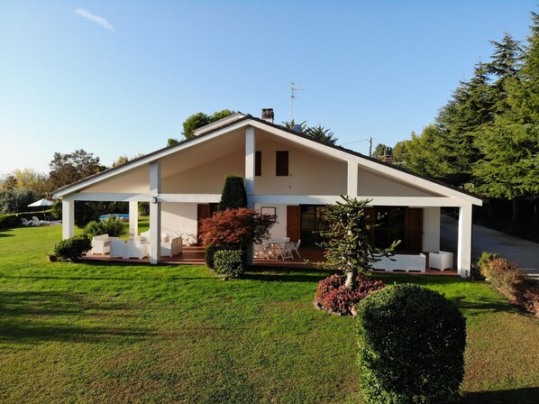 A modern two-story house with a covered patio, a lawn, and a driveway.