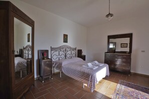 A bedroom with a bed, dresser, mirror, and tiled floor.