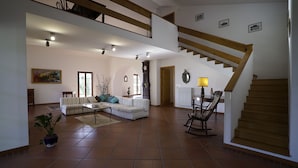 Amplia sala de estar con techo alto, una escalera y un comedor.