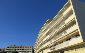 A multi-story hotel with balconies and a clear blue sky.