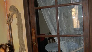 Une porte en bois ornée d’un rideau en dentelle, une petite chaise et une commode en bois.