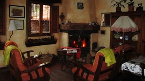 Un salon chaleureux avec une cheminée, des meubles en bois et une fenêtre agrémentée de rideaux.