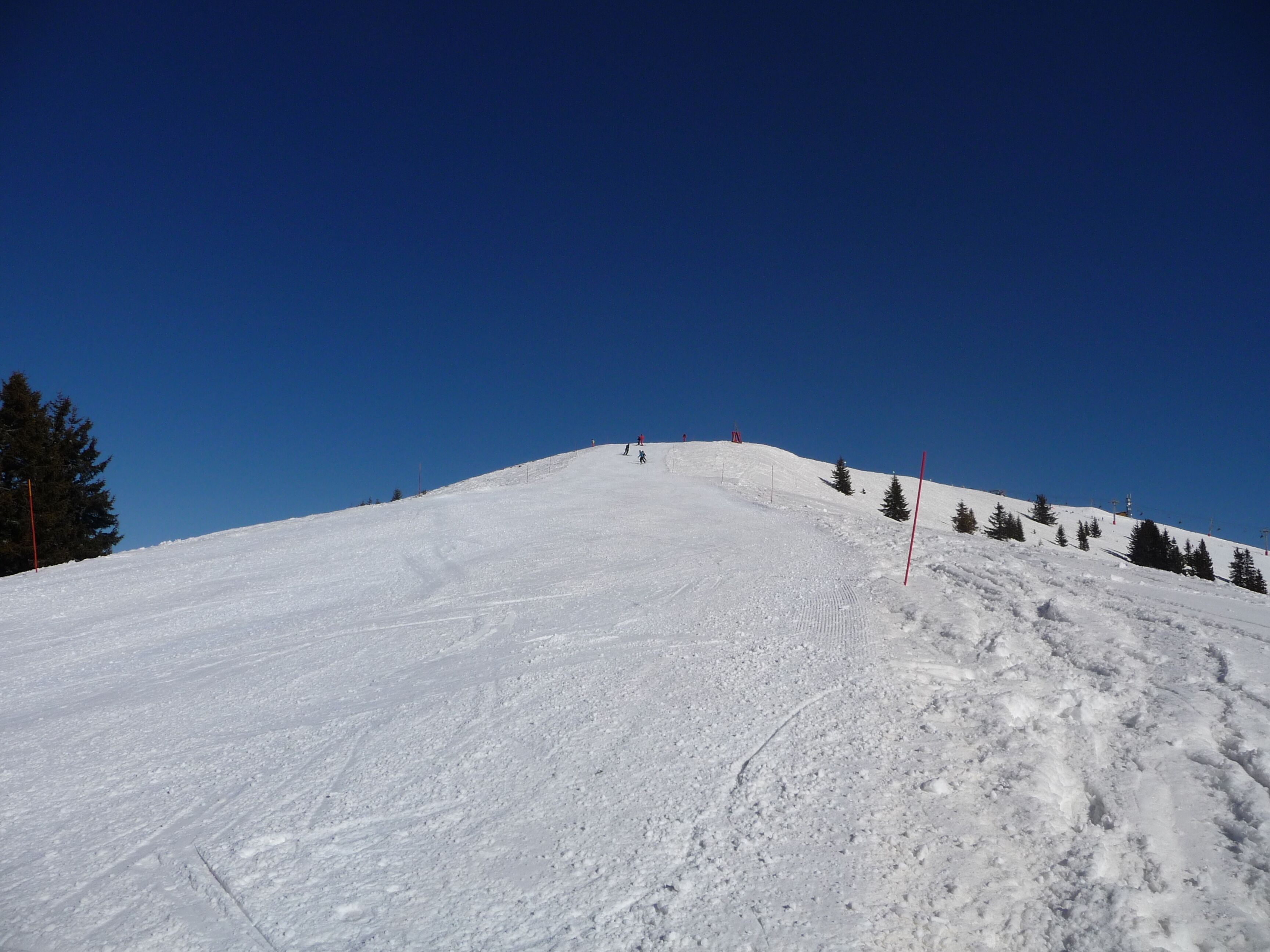 A snowy ski slope with a clear blue sky.