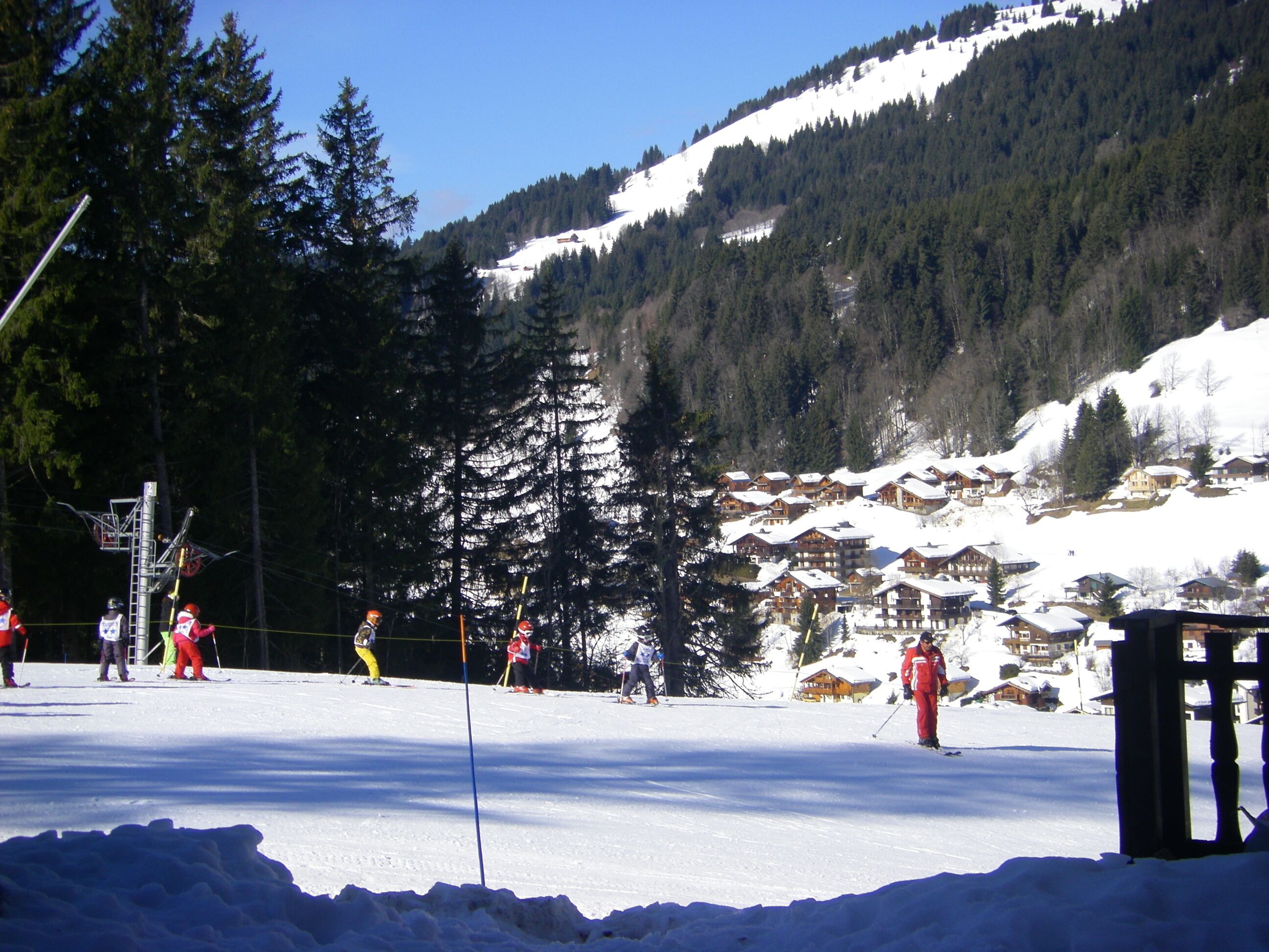 Une station de ski avec des pistes enneigées, des chalets en bois et une montagne boisée en toile de fond.