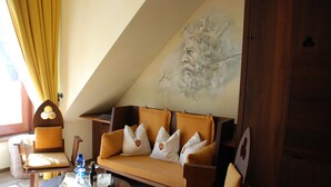 A cozy room with a sofa, chairs, a small table, and a mural on the wall. - Mittelalterhotel-Gästehaus Rauchfang (Meersburg)