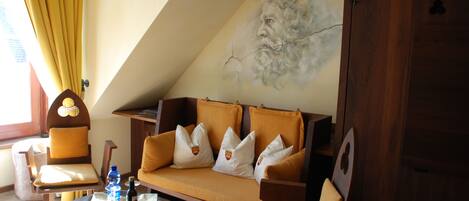 Une pièce chaleureuse avec un canapé, des fauteuils, une petite table et une fresque murale.