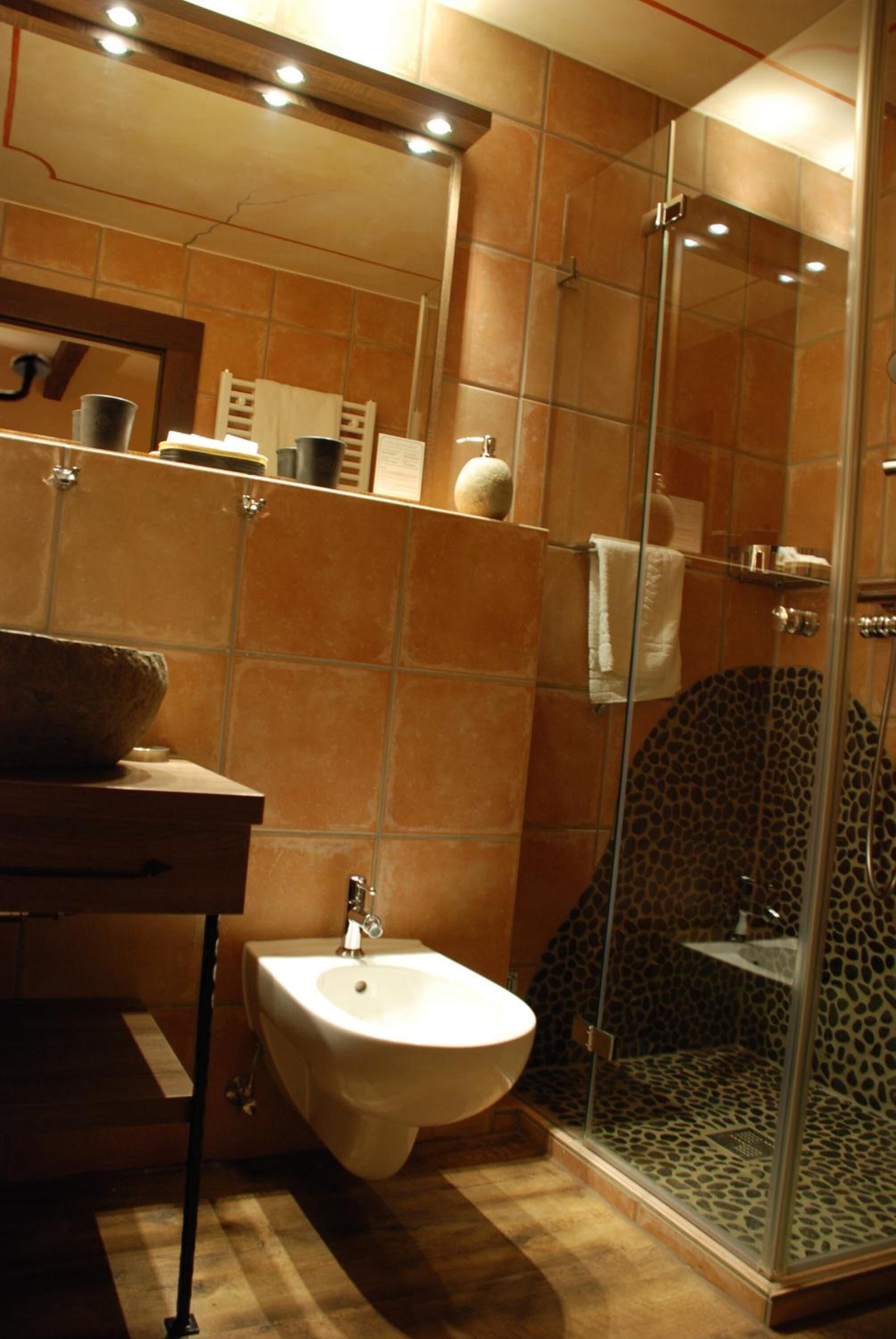 Ein Badezimmer mit integriertem Bidet, einer gläsernen Duschkabine und einer gefliesten Wand.