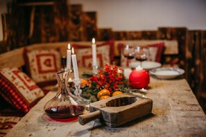 Ein rustikaler Holztisch mit einer alten Weinkaraffe, Kerzen und einer Obstschale.
