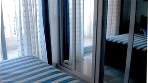 Habitación de hotel con dos camas, una puerta corrediza de vidrio y vista al balcón exterior.