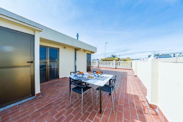 A terrace with a table set for two, a brick floor, and a view of the cityscape. - Nice chalet house in Perellonet (Valencia)