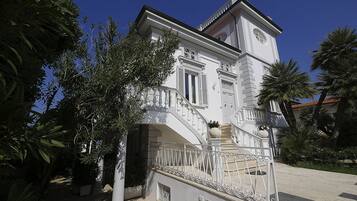 A white building with a clock tower, a staircase, and a balcony.