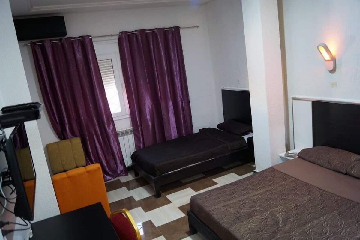 A compact hotel room with a single bed, a desk with a chair, a small table, and a television.
