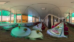 Una larga mesa de comedor con sillas, ventanas amplias y vistas a la ciudad.