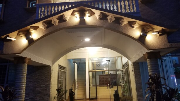 An entrance with a stone archway, a staircase, and a glass door leading inside. - Medrie International Hotel (Freetown)