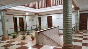 A spacious lobby with a checkered floor, a central staircase, and columns with decorative bases. - Medrie International Hotel (Freetown)