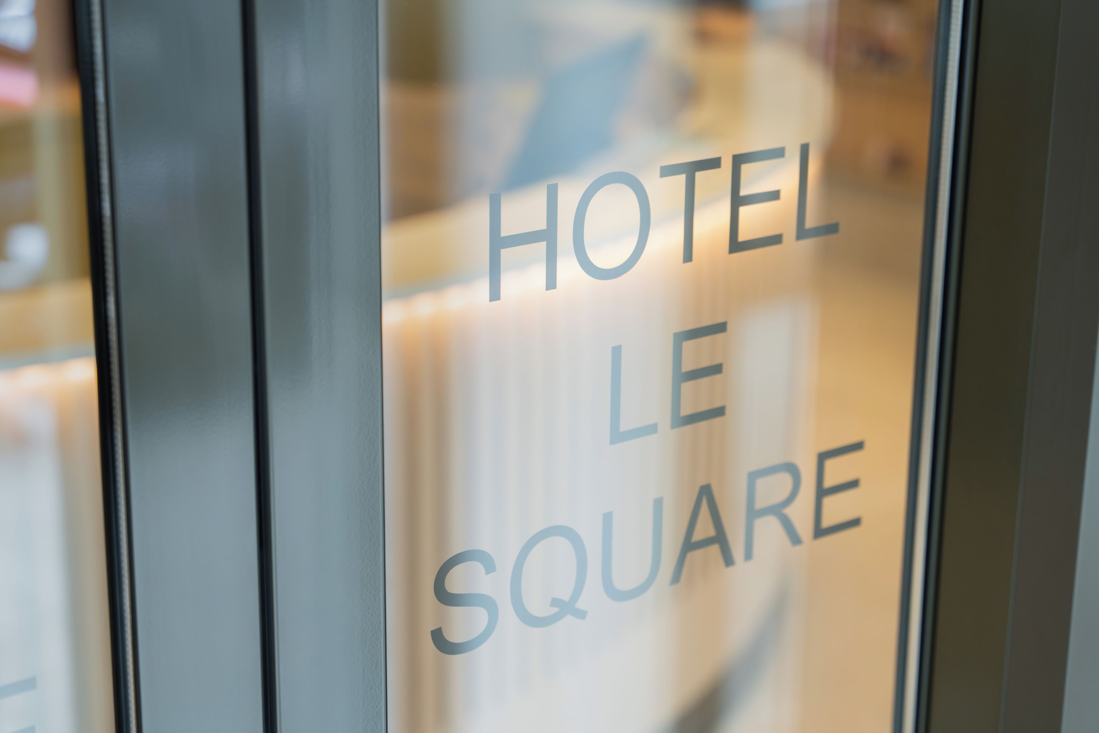 A glass door with the text 'HOTEL LE SQUARE' indicating the name of the establishment.