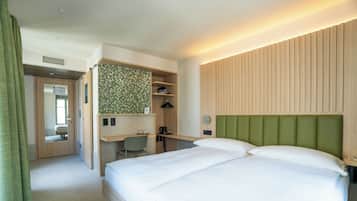 A hotel room with a bed, a desk, and a green headboard.