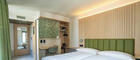 A hotel room with a bed, a desk, and a green headboard.