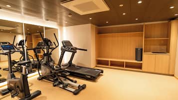 A gym with exercise equipment, wooden cabinets, and a mirror.