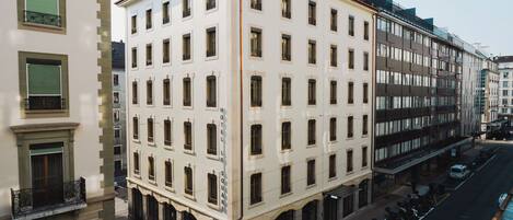 Un hotel de varios pisos con un estilo arquitectónico clásico, que cuenta con una entrada central, múltiples ventanas y un área de estacionamiento.