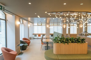 A modern office space with a curved seating area, a central table, and a plant centerpiece. - Le Square (Geneva)